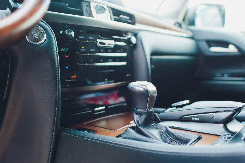 Close-up of a car's center console featuring the gear shift, push-to-start button, and dashboard controls.