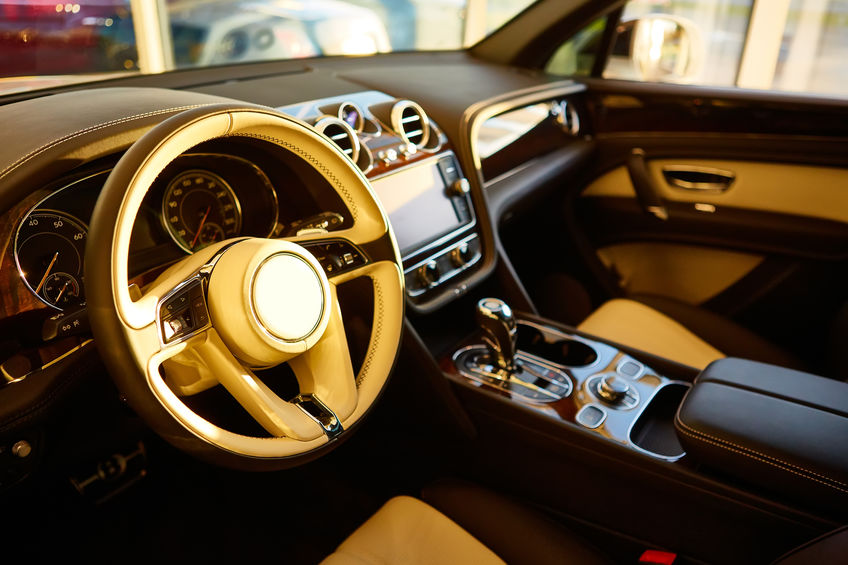 Luxury car interior with beige leather seats, wood trim, modern dashboard, and touchscreen display in the center console.